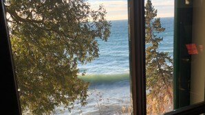 Blick durch ein Fenster mit Geländer auf eine verschneite Landschaft und ein Gewässer.