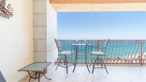 Ein Balkon mit zwei Stühlen und einem kleinen Tisch, mit Blick auf das klare, blaue Meer.