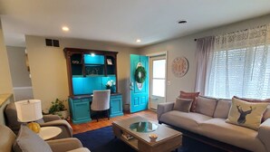 A living room with a sofa set, a coffee table, a blue cabinet, and a door with a wreath. - Summer House private pool/lake/large backyard/fire pit (Virginia Beach)
