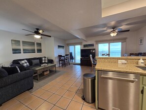 A spacious living area with a sofa, TV, dining table, and kitchen counter. - West Coast Vistas  Beach front 3 bedrooms two bath 1D (Indian Rocks Beach)