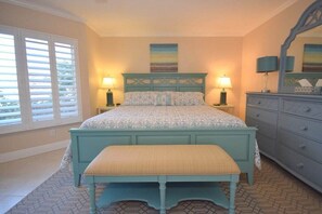 Une chambre à coucher comprenant un lit, un banc, une commode et une fenêtre avec des stores.