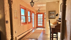 Un couloir avec un plancher en bois, un tapis et une chaise.