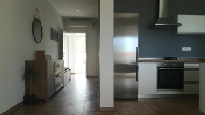 Eine moderne Küche mit Edelstahlgeräten, Holzboden und Blick in den Wohnbereich.