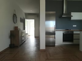 Una cocina moderna con electrodomésticos de acero inoxidable, piso de madera y vista al área de estar.