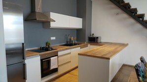 Eine moderne Küche mit einem Edelstahl-Kühlschrank, einem eingebauten Backofen, einer Mikrowelle und einer Holz Arbeitsplatte.