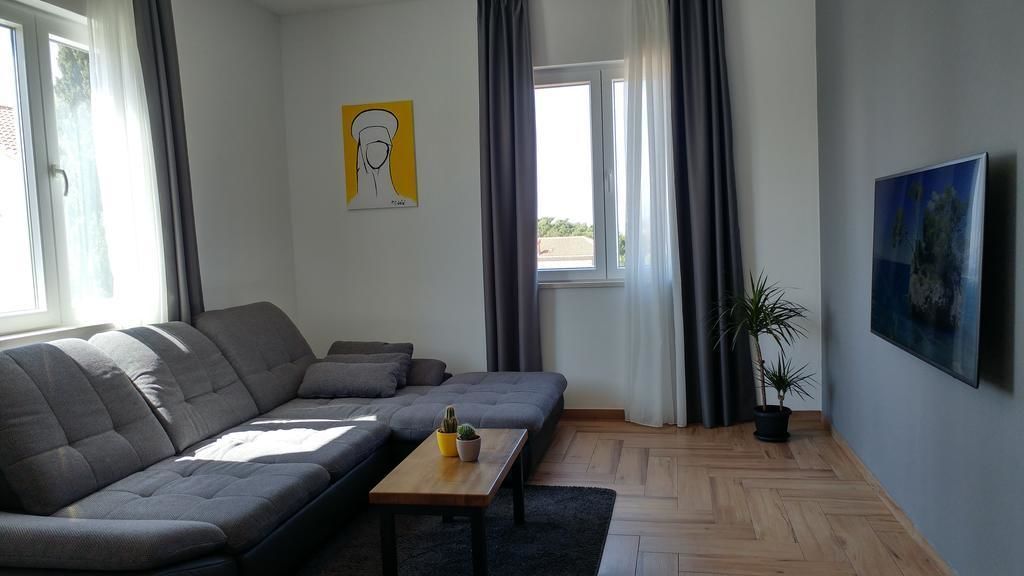 A modern living room with a grey sectional sofa, a small wooden table, and a potted plant.