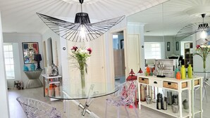 Un comedor moderno con una mesa de vidrio, sillas transparentes y una lámpara colgante decorativa.