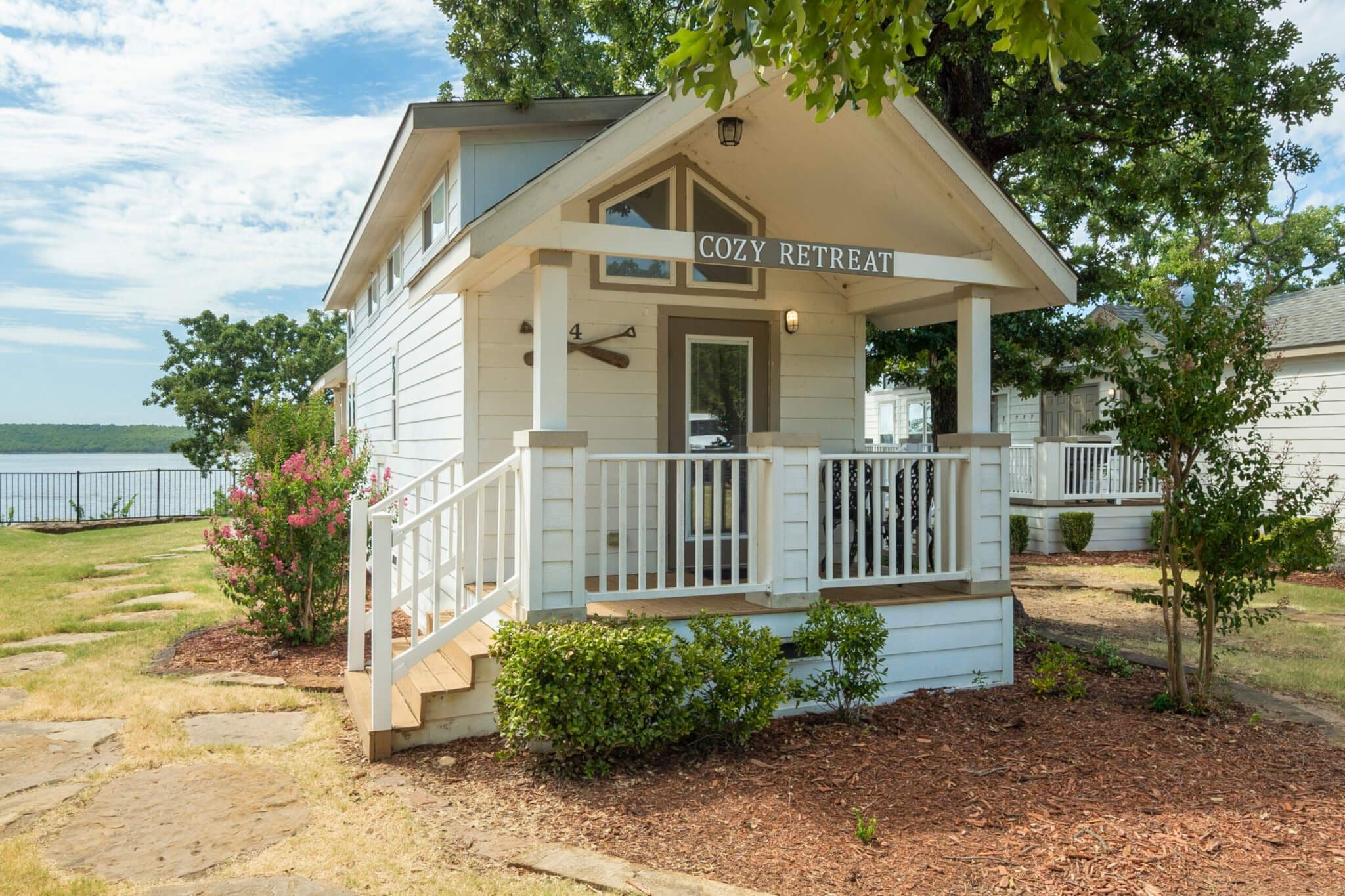 A cozy retreat with a porch, a sign reading "COZY RETREAT", and a view of the lake.