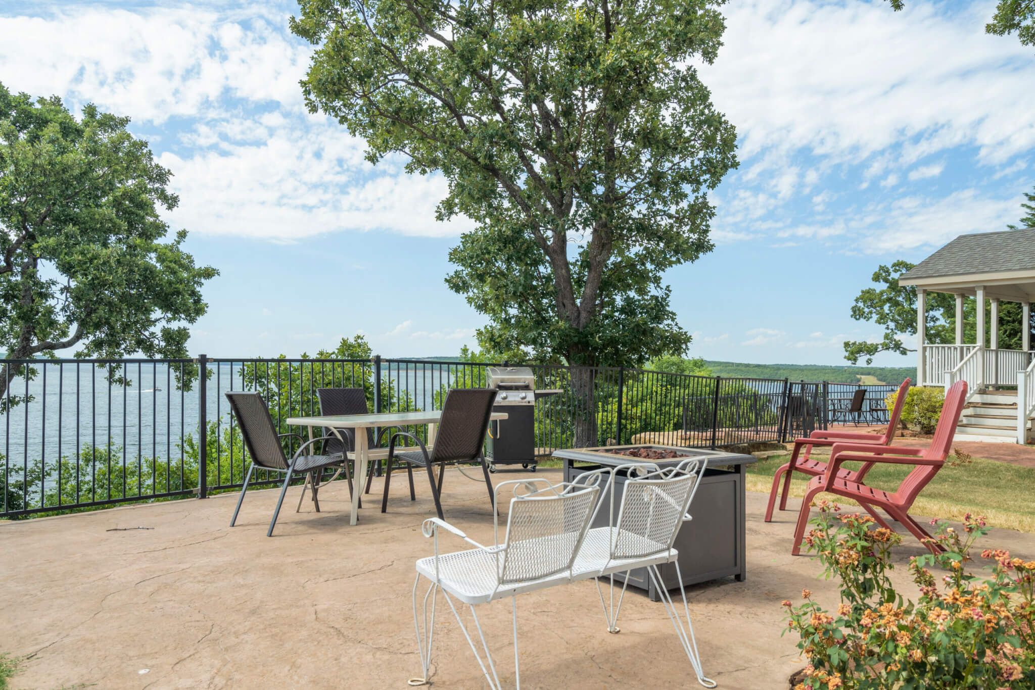 An outdoor patio with a grill, chairs, and a view of the lake.