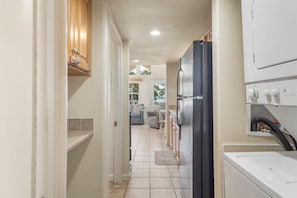 A kitchen with a refrigerator, washing machine, and cabinets. - Cozy Retreat at CrossTimbers Marina (sperry)
