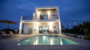 Une maison moderne à deux étages avec une piscine à l’avant.