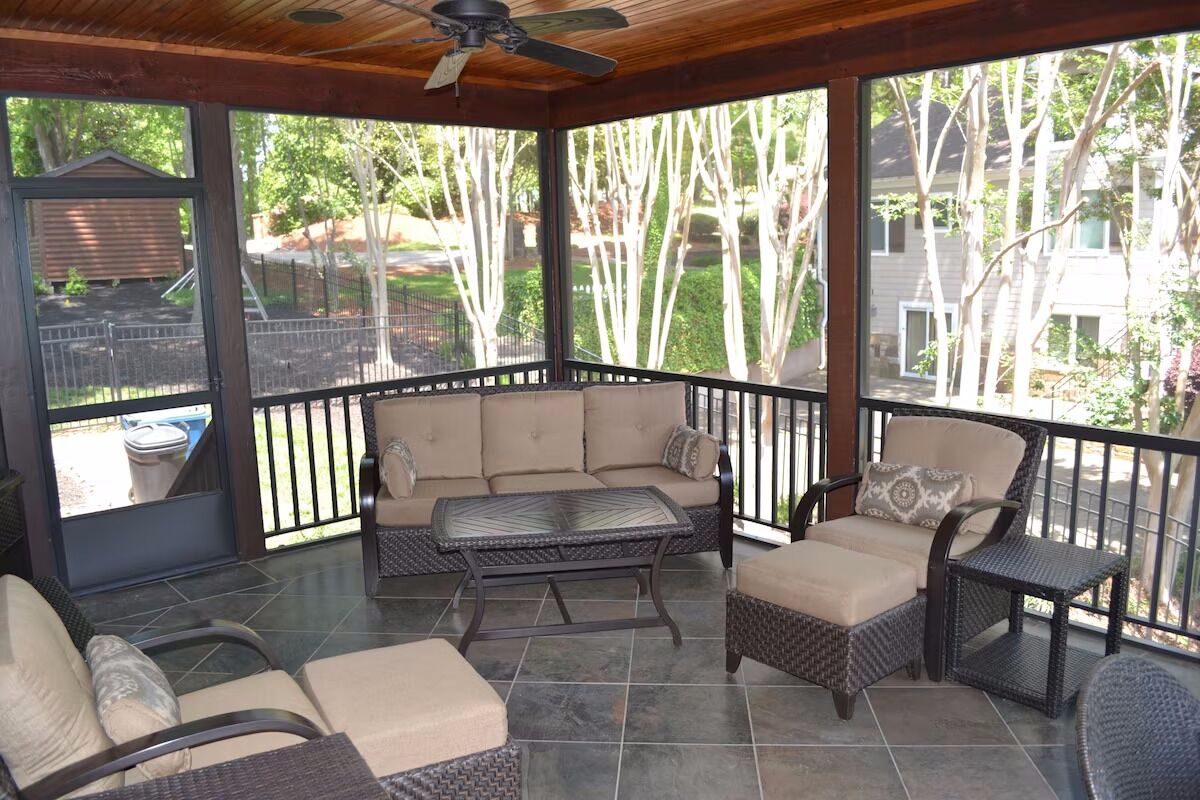 A covered patio area with a sofa, chairs, and a table.