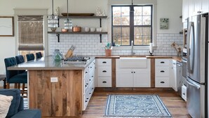 A modern kitchen with a central island, white cabinetry, and stainless steel appliances.