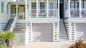 Et tosidet hus med en overdækket veranda, en garage foran og en trappe op til øverste etage.