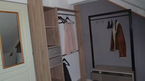 Ein Zimmer mit Holzschrank, Spiegel, Bank und Kleiderstange.
