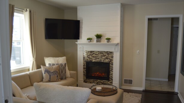A living room with a fireplace, a sofa, and a television mounted on the wall. - ★★★★★Charlevoix 5 Star-rated Cottage★★★★★ (Charlevoix)