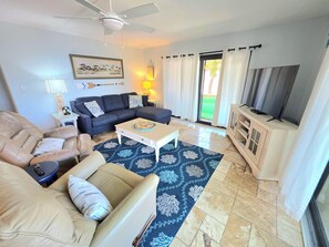 A living room with a sofa, armchair, coffee table, and a television on a cabinet. - ON Siesta Key BEACH! Pool,Remodeled! 2bd2ba, sleeps 6, 3mins from door to sand   (Sarasota)