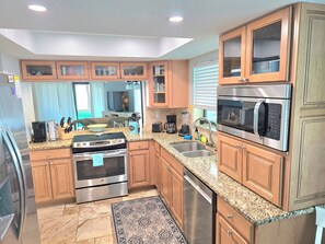 A modern kitchen with granite countertops, stainless steel appliances, wooden cabinets, and a built-in dishwasher. - ON Siesta Key BEACH! Pool,Remodeled! 2bd2ba, sleeps 6, 3mins from door to sand   (Sarasota)