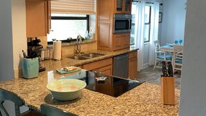A kitchen with granite countertops, wooden cabinets, and a backsplash. There is a sign above the sink that reads "SIESTA LIVING THE DREAM KEY FL."