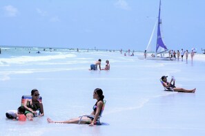 A beach with people sunbathing and a sailboat in the water. - ON Siesta Key BEACH! Pool,Remodeled! 2bd2ba, sleeps 6, 3mins from door to sand   (Sarasota)