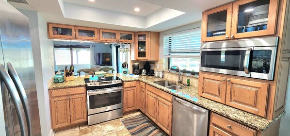A modern kitchen with wooden cabinets, stainless steel appliances, and a granite countertop.