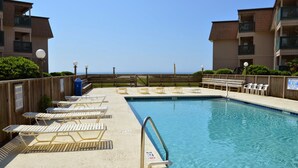 Un espace piscine avec des chaises longues et vue sur l’océan.