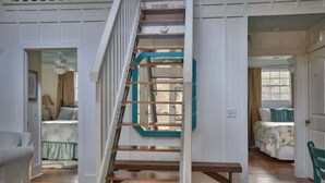 A staircase with a wooden handrail and teal accents, leading to a bedroom with a bed and a window.