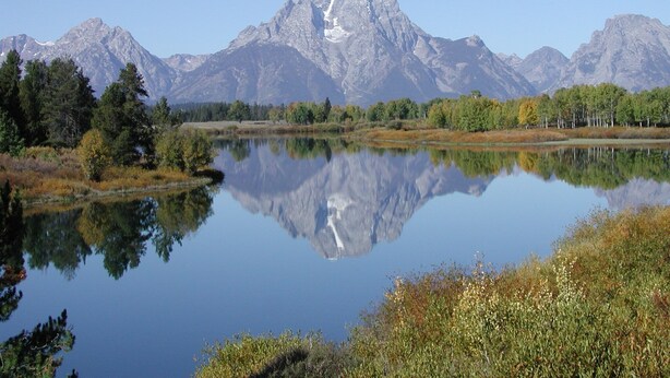 Berglandschap met een helder meer dat de bergtoppen weerspiegelt.