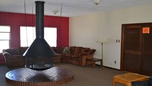 A living room with a brick fireplace, a brown leather couch, a wooden coffee table, and a red brick wall. - 2 Bed 2 Bath Family Ski Condo (Pet Friendly!) (Dillon)