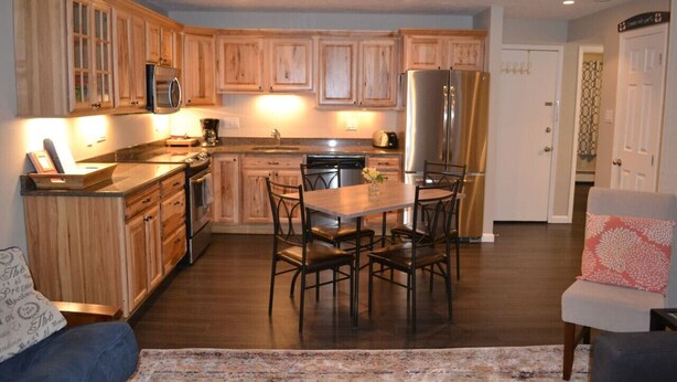 A modern kitchen with wooden cabinets, stainless steel appliances, and a dining area with a table and chairs. - 2 Bed 2 Bath Family Ski Condo (Pet Friendly!) (Dillon)