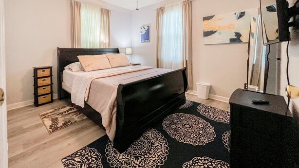 Ein Schlafzimmer mit Bett, Deckenventilator, Kommode, Spiegel und Teppich.
