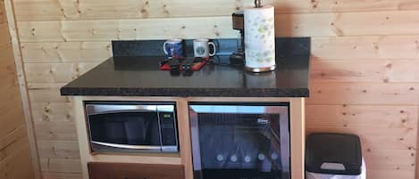 Una cocina compacta con microondas, un refrigerador Danby y una cafetera sobre la encimera.