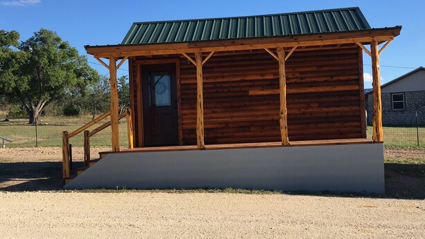 A wooden cabin with a metal roof, a front door, and a small porch with a single step. - Crooked Creek Ranch Cabin 2 (Hamilton)
