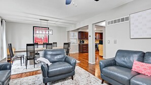 A modern living room with leather sofas, a dining area, and a kitchen in the background. - 🌻Luxury King Beds🌻Nearby Parks🌻 Reserved Parking🌻Smart TVs🌻Google Fiber🌻 (Overland Park)