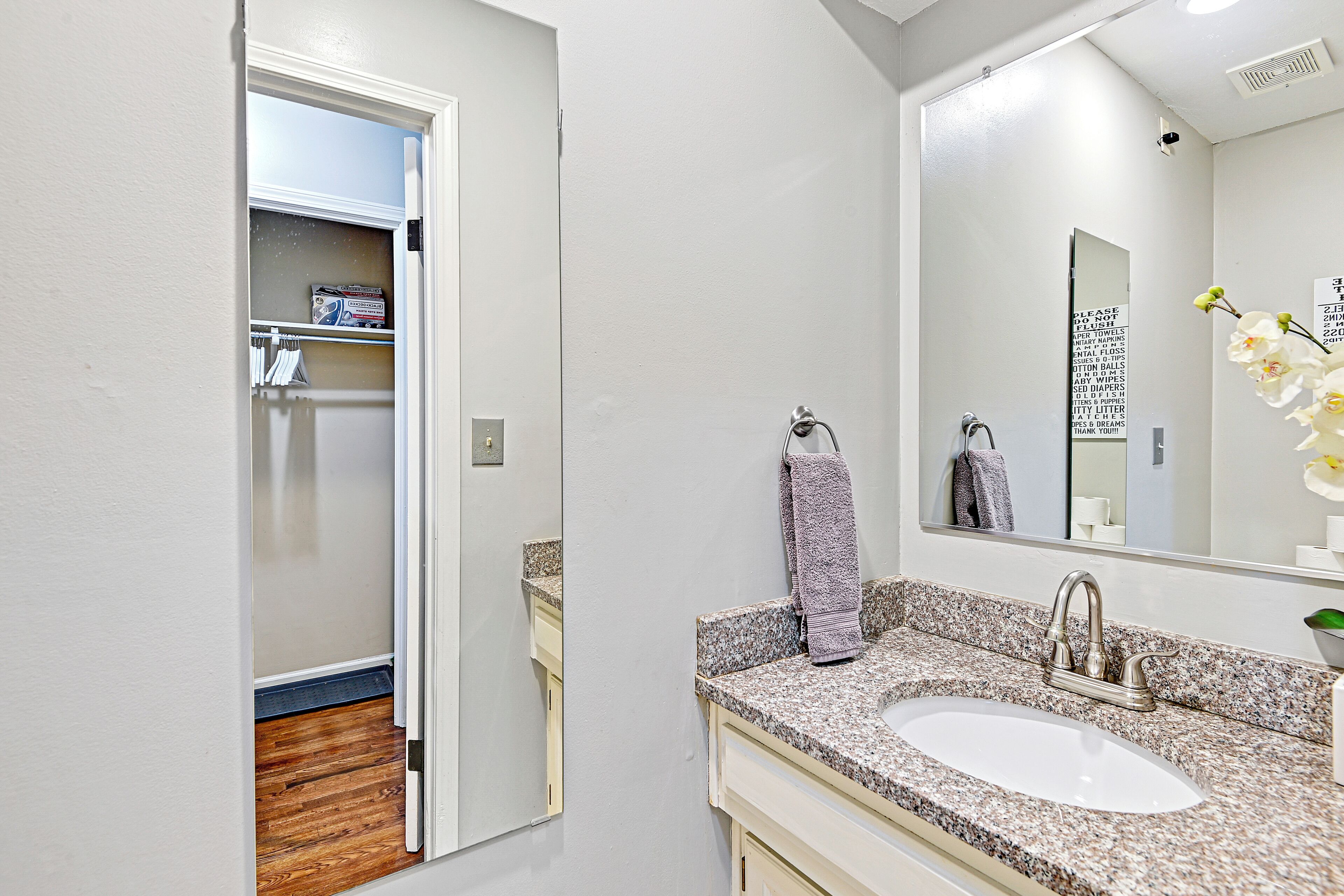 A modern bathroom with a granite countertop sink, a large mirror, and a towel rack.