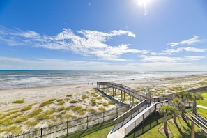 A beach with a wooden boardwalk and palm trees.