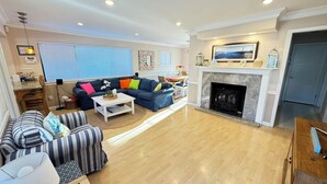 A living room with a fireplace, a sofa set, a dining area, and a kitchen visible through an open door. - Bright and Colorful - Family Friendly!  Short walk to the Best Beaches in Town! (Santa Cruz)