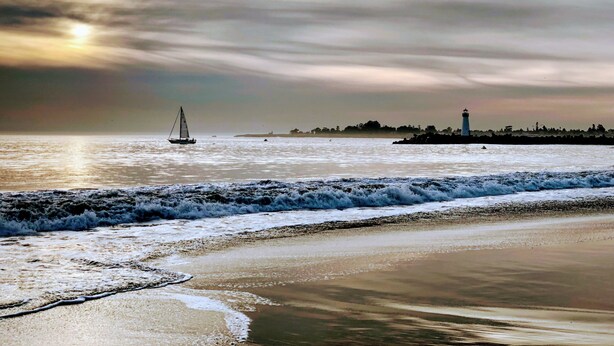 A beach with waves, a sailboat, and a lighthouse in the distance. - Bright and Colorful - Family Friendly!  Short walk to the Best Beaches in Town! (Santa Cruz)
