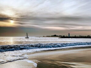A beach with waves, a sailboat, and a lighthouse in the distance. - Bright and Colorful - Family Friendly!  Short walk to the Best Beaches in Town! (Santa Cruz)