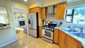 A modern kitchen with stainless steel appliances, wooden cabinets, and a large window providing a view of the outdoors. - Bright and Colorful - Family Friendly!  Short walk to the Best Beaches in Town! (Santa Cruz)
