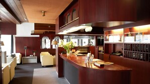 Un vestíbulo de hotel con mostrador de recepción, zona de estar y vistas al comedor.