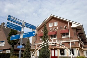 A hotel with a sign indicating directions to nearby locations. - Hotel De Prins (Sittard)