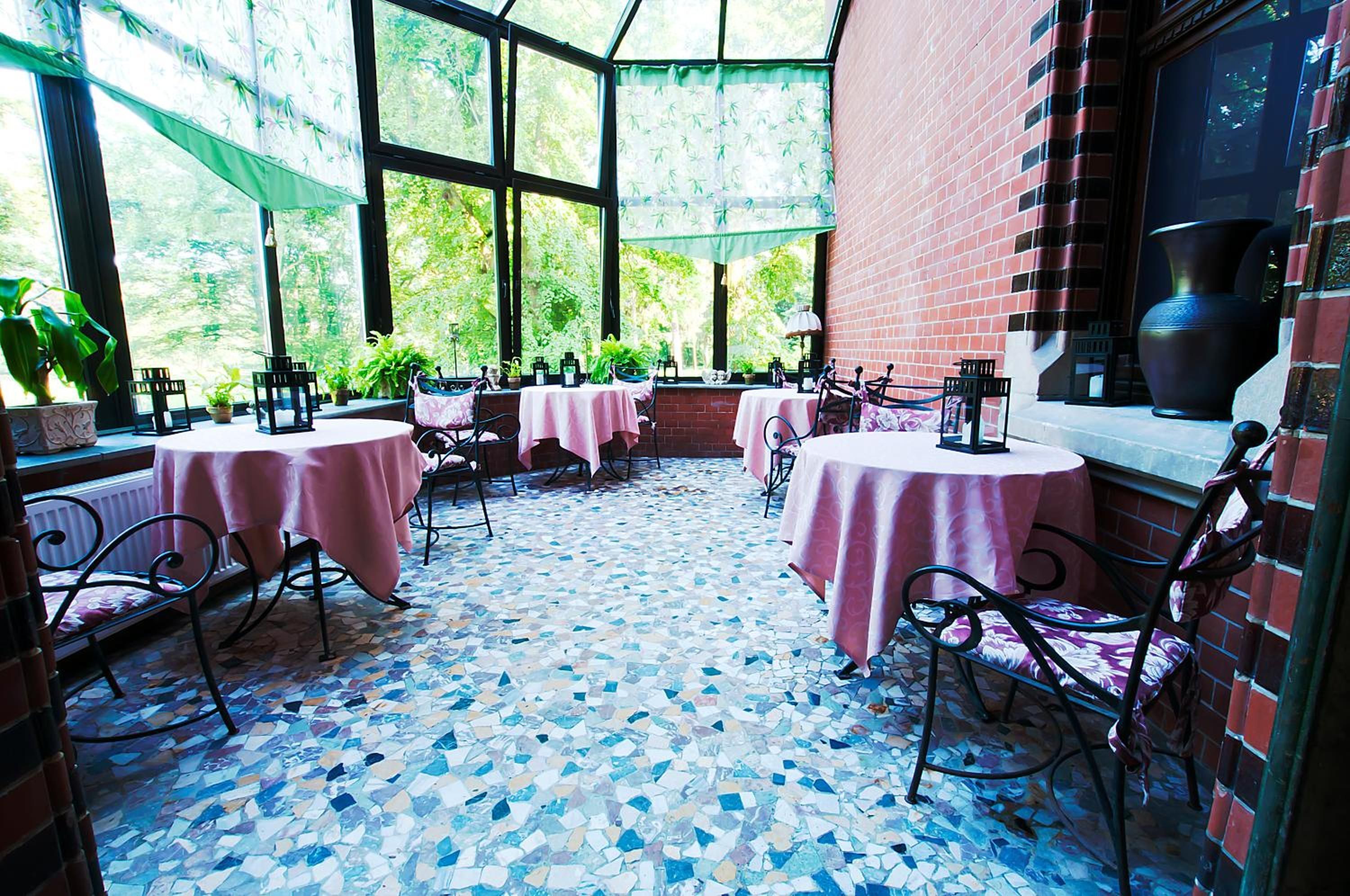 An outdoor patio area with tables and chairs, a tiled floor, and a brick wall.