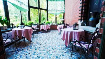 An outdoor patio area with tables and chairs, a tiled floor, and a brick wall.