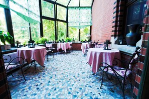 An outdoor patio area with tables and chairs, a tiled floor, and a brick wall.