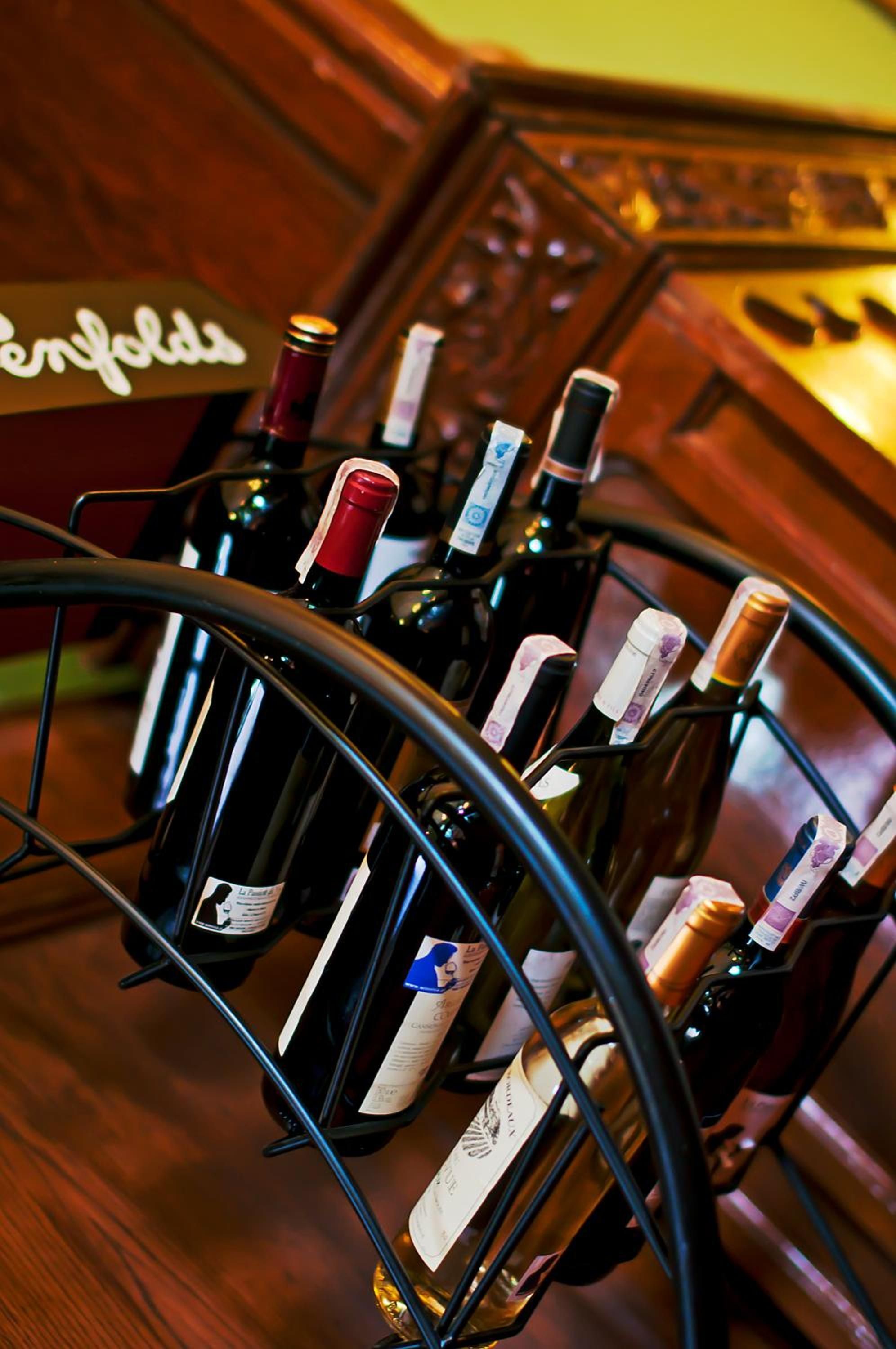 A wine rack with multiple bottles, some with corks, and a wooden cabinet in the background.