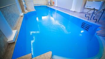 A swimming pool with a clear blue water, a diving board, and a lifebuoy on the wall.