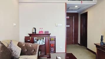 Una sala de estar con un sofá, un mueble de madera con diversos objetos, y un pasillo que conduce a una puerta.