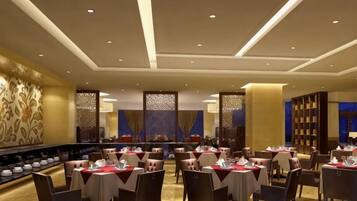 A dining area with tables set for service, a long counter with a display of dishes, and a patterned wall.