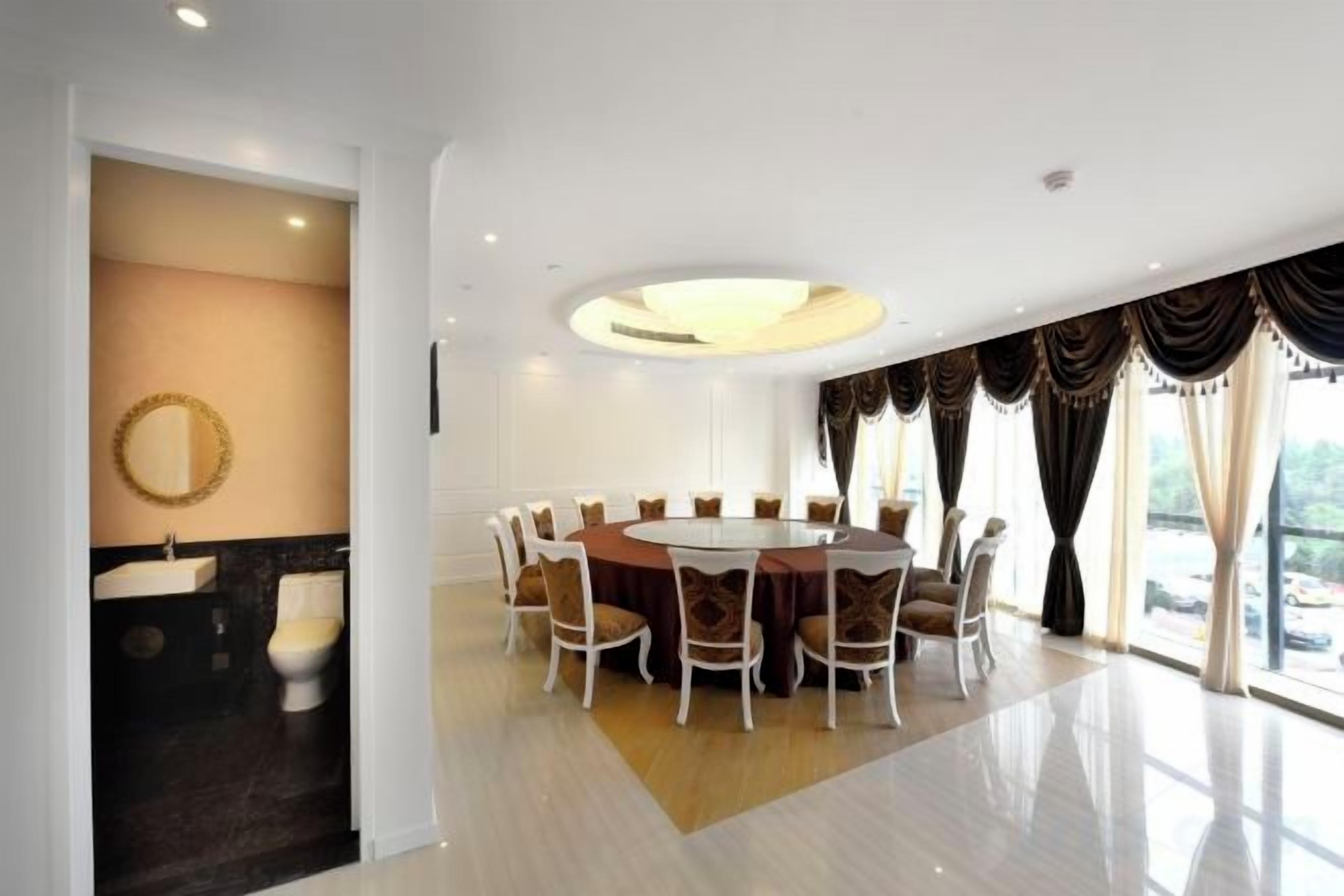 Comedor moderno con una mesa redonda y sillas, un espejo grande y vistas al exterior.